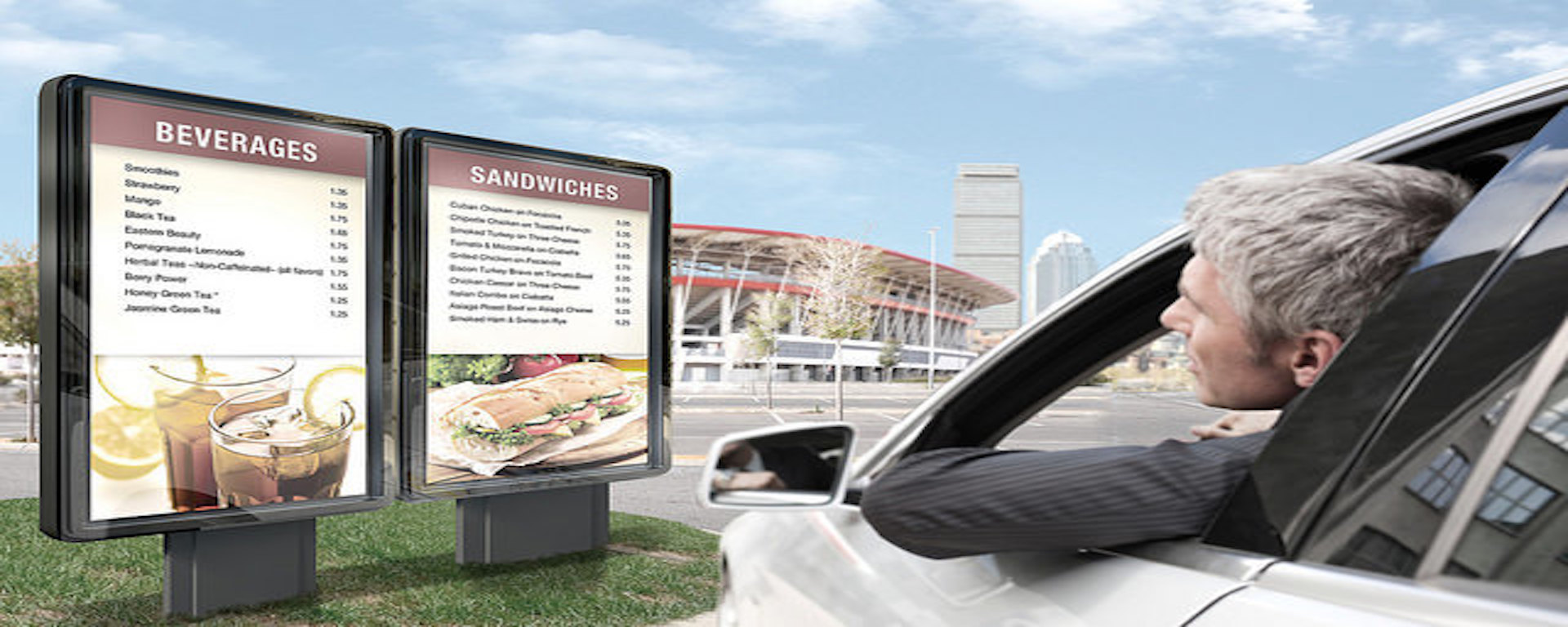 A guy in car looking at outdoor digital menu boards