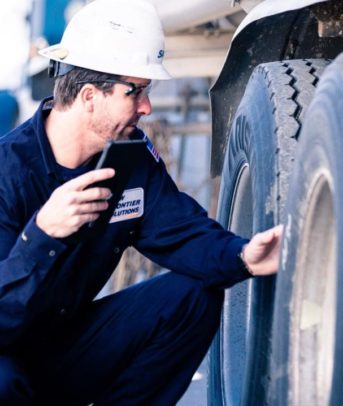 Man performs maintenance on 18-wheeler truck.