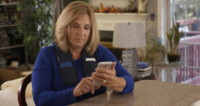 Woman using smart programmer to optimize DBS therapy.