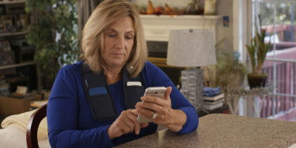 Woman using smart programmer to optimize DBS therapy.