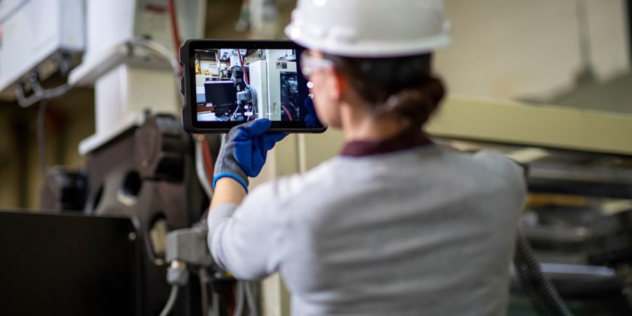 a worker performs a preventative maintenance inspection with a tablet