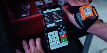 A warehouse worker pushes a cart with wearable scanner and picking solution