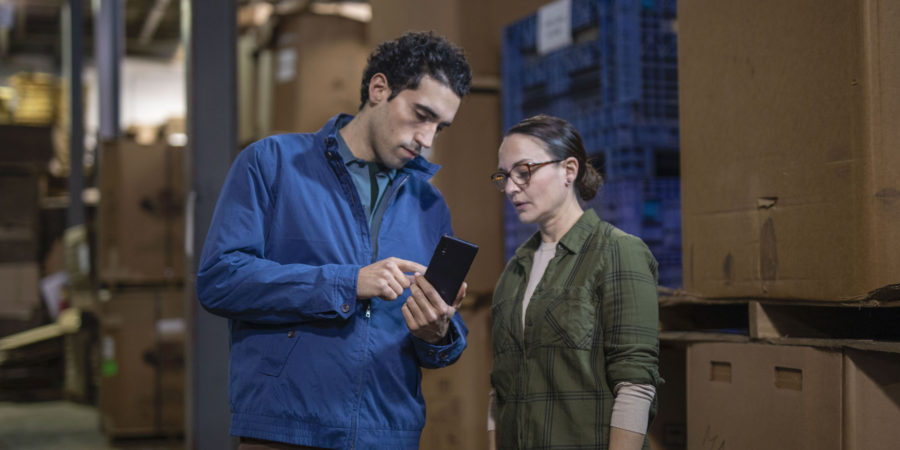 Two warehouse workers use a Samsung Galaxy XCover Pro for inventory management