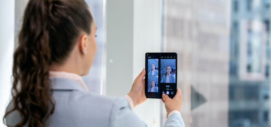 Businesswoman in office taking selfies while reviewing shots with Capture View on her Galaxy Z Fold3