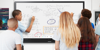 Two students writing on interactive whiteboard in front of classroom