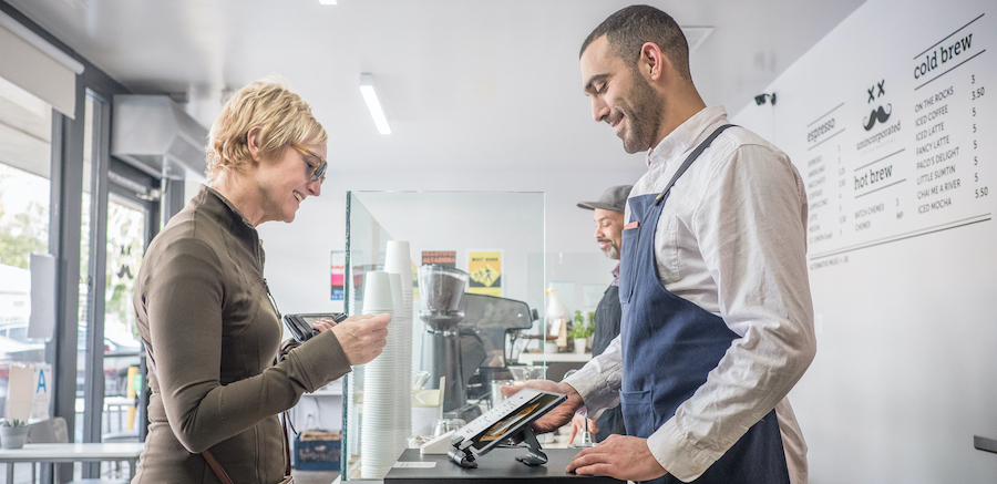 Woman paying at tablet kiosk in a cafe