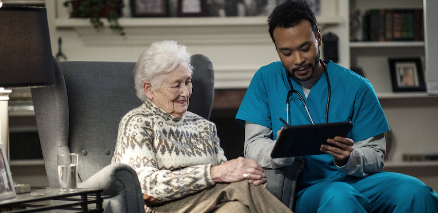 Nurse taking down information at patient's home on dedicated healthcare tablet