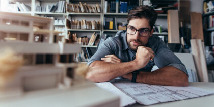 Young professional working on blueprints with architectural model