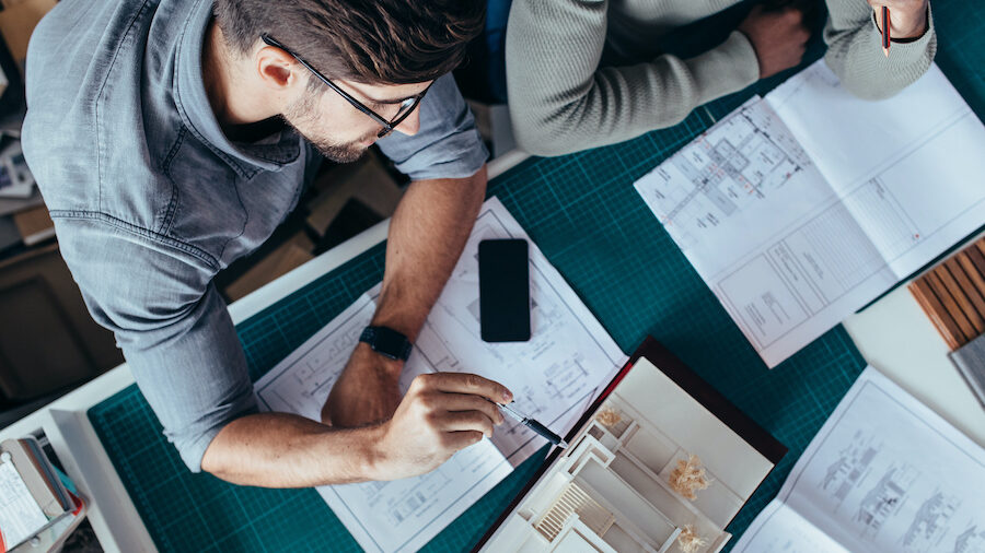 Top view of two male architects sitting in office and working on project. Creative people working on new architectural house model