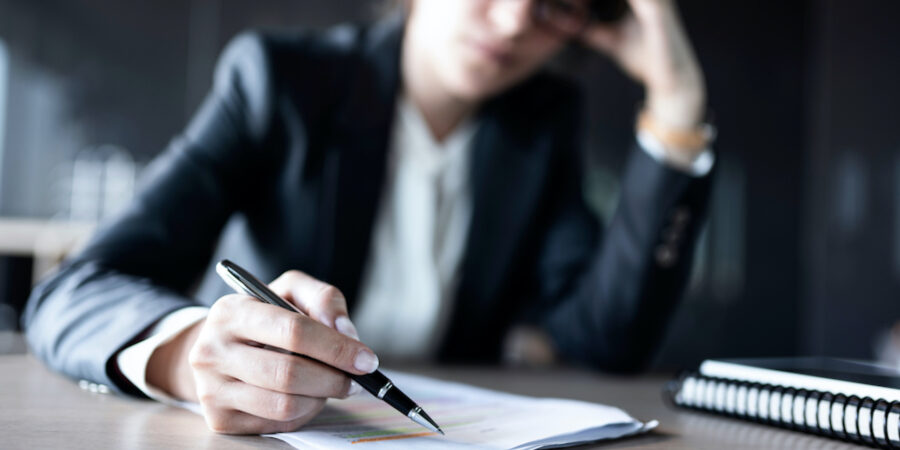 A close-up shot of a businessperson's hand writing on a paper form.