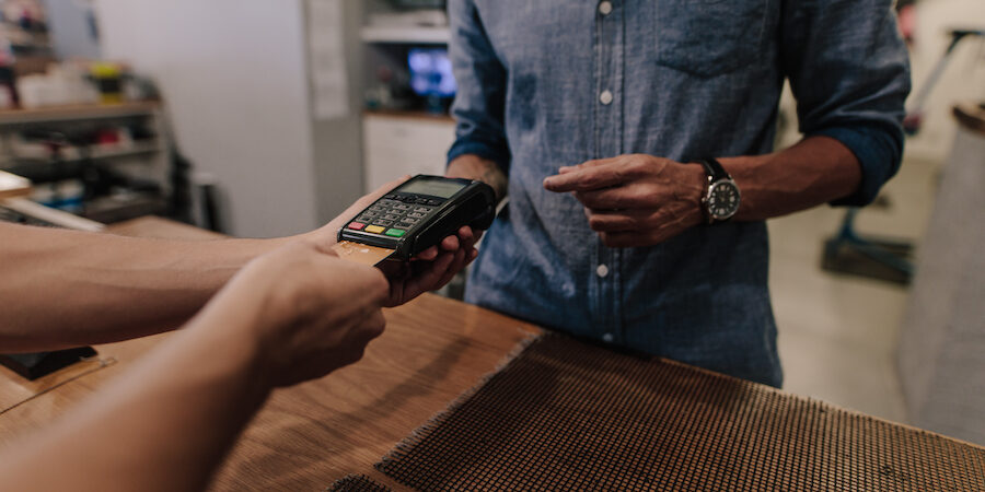 Shop owner accepting payment using credit card. Cropped shot of man inserting credit card in payment machine.