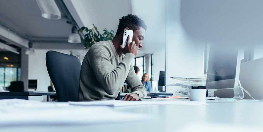 Small business employee talking on smartphone at desk