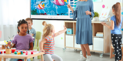 In an elementary school classroom, a teacher leads a science lesson on an interactive whiteboard.