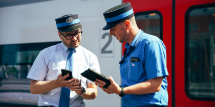 Belgian Railway agents confer in front of train car using Samsung tablets