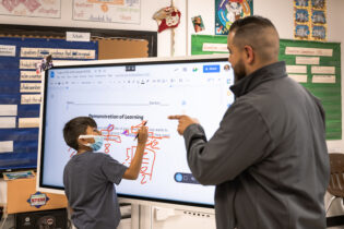 Teacher shows student how to use Samsung display in classroom