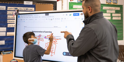 Teacher shows student how to use Samsung display in classroom