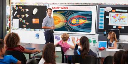 Teacher uses interactive whiteboard to teach elementary school students.