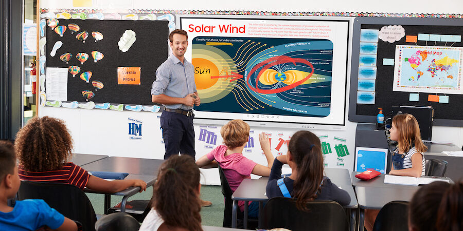 Teacher uses interactive whiteboard to teach elementary school students.