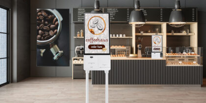 The inside of a coffee shop with a white, sleek self service kiosk