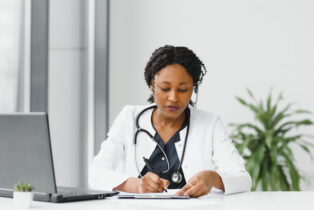 Doctor sitting at desk writing on notepad