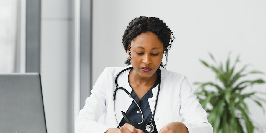 Doctor sitting at desk writing on notepad